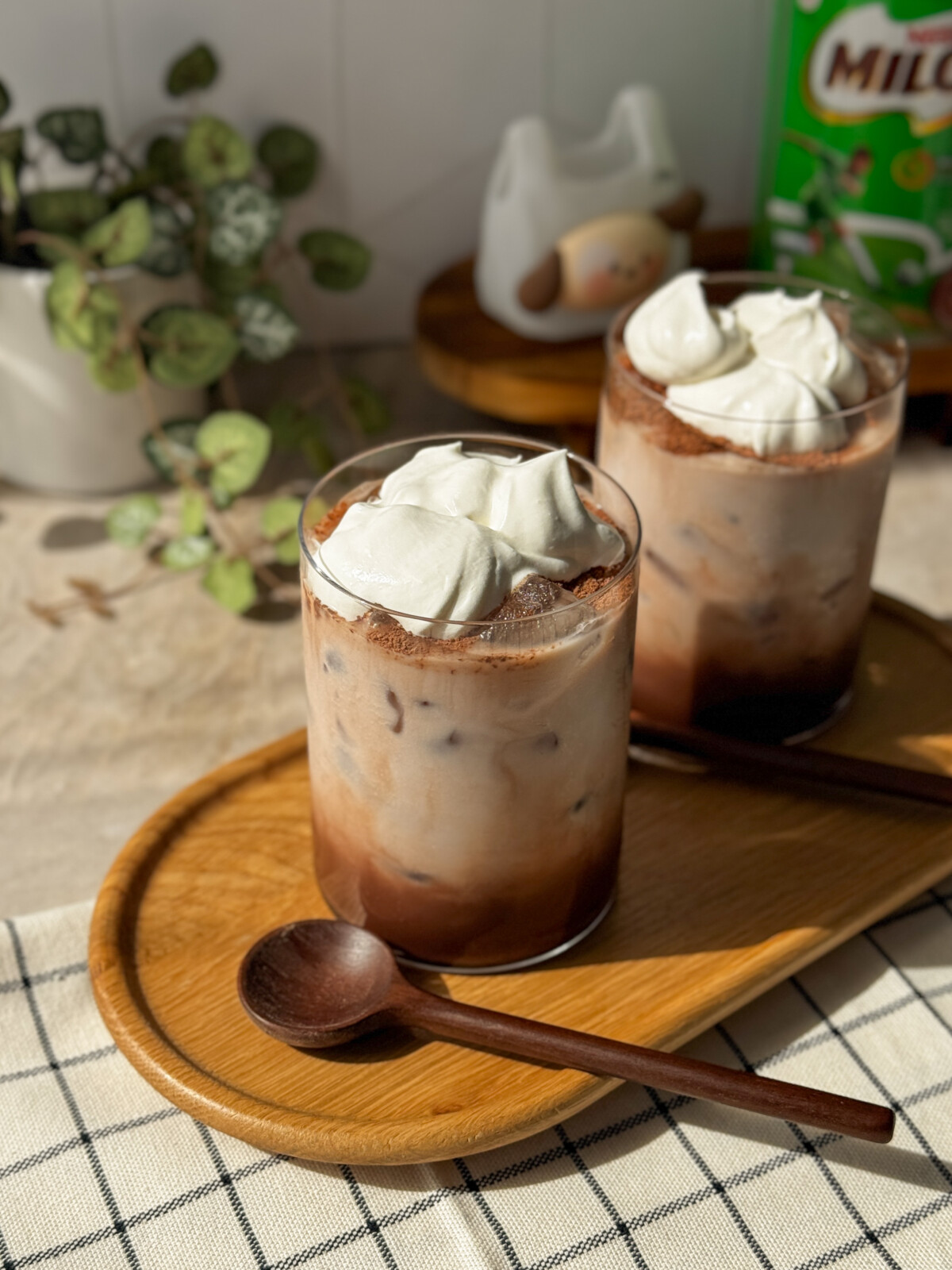 Tall glass of iced Milo with whipped cream and Milo powder dusted on top