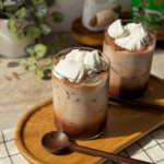 Tall glass of iced Milo with whipped cream and Milo powder dusted on top