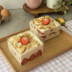 Strawberry vanilla pudding served in two boxes, layered with vanilla wafers, macerated strawberries, and whipped cream