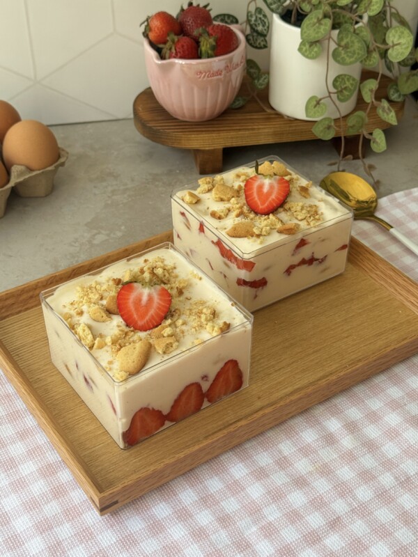 Strawberry vanilla pudding served in two boxes, layered with vanilla wafers, macerated strawberries, and whipped cream